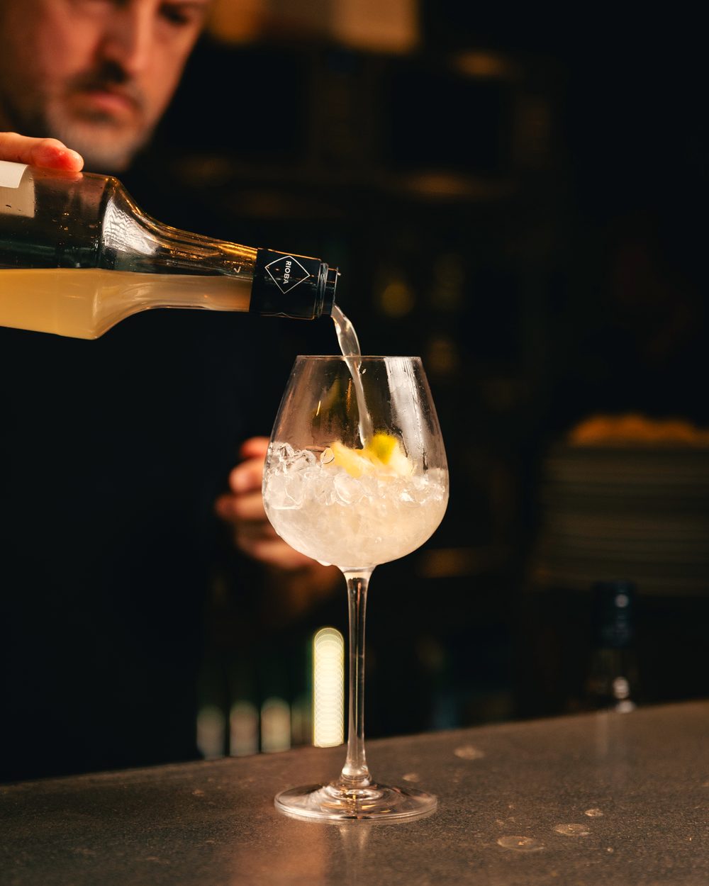 Service d’un alcool clair dans un verre à pied rempli de glace pilée.