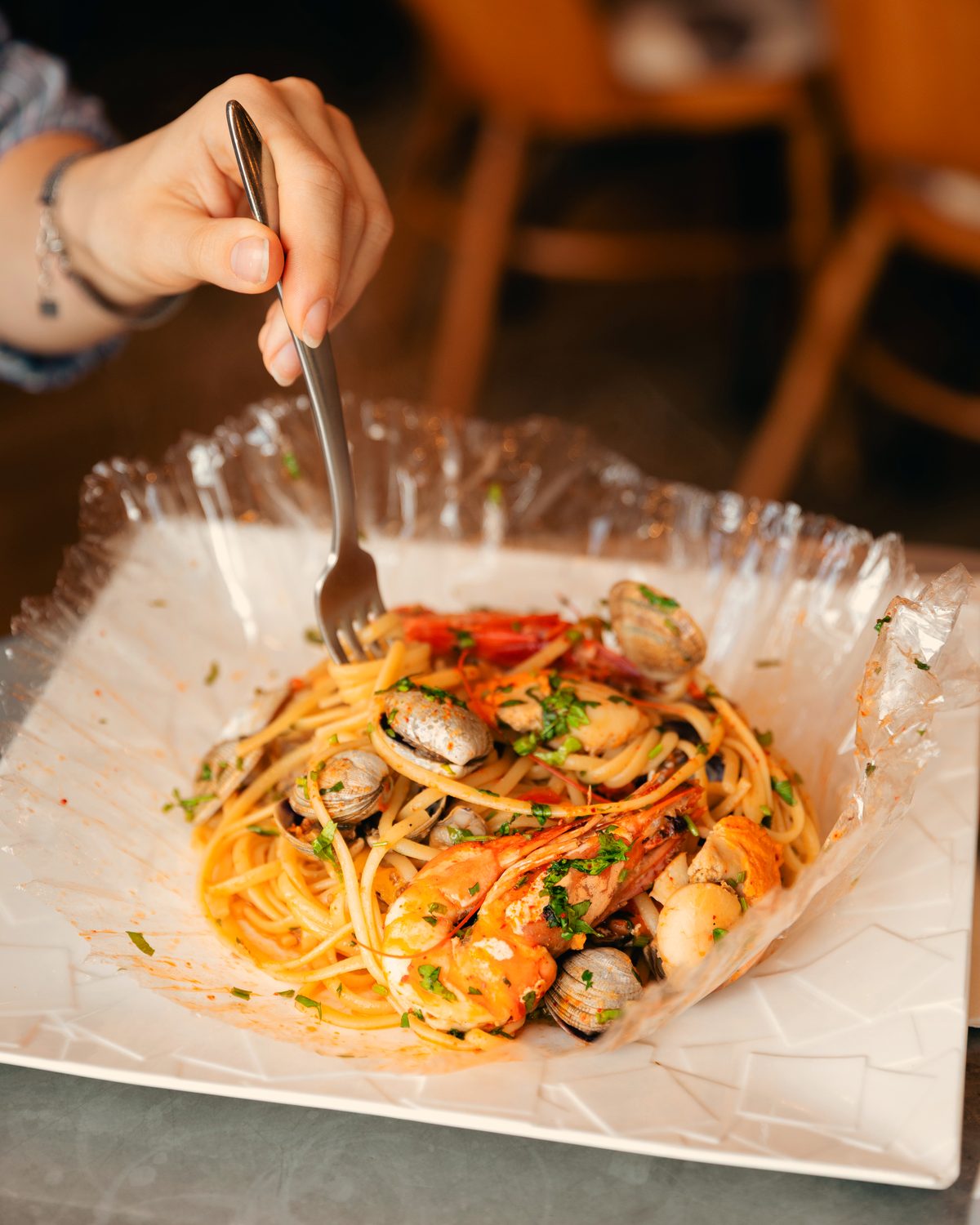Linguine aux fruits de mer servies dans leur papillote ouverte.